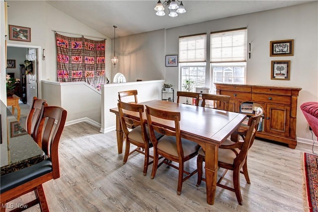 dining space featuring lofted ceiling, light wood finished floors, and baseboards