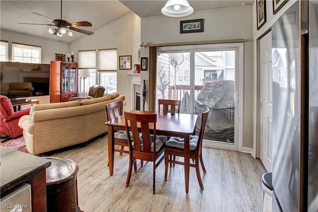 dining room with light wood-style floors, lofted ceiling, and a ceiling fan