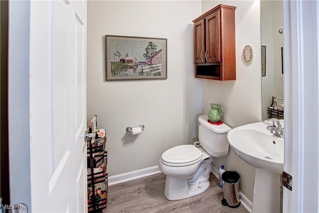 bathroom featuring a sink, wood finished floors, toilet, and baseboards