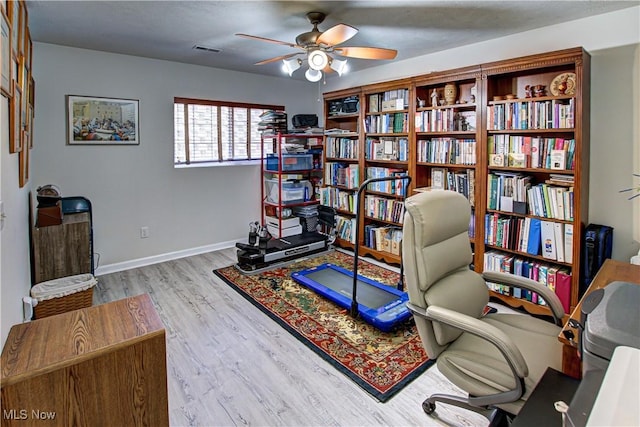 home office with visible vents, ceiling fan, baseboards, and wood finished floors