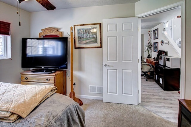 bedroom featuring light carpet, baseboards, visible vents, and ceiling fan