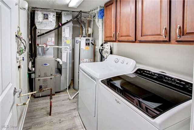 washroom with gas water heater, light wood-style floors, cabinet space, heating unit, and washing machine and clothes dryer