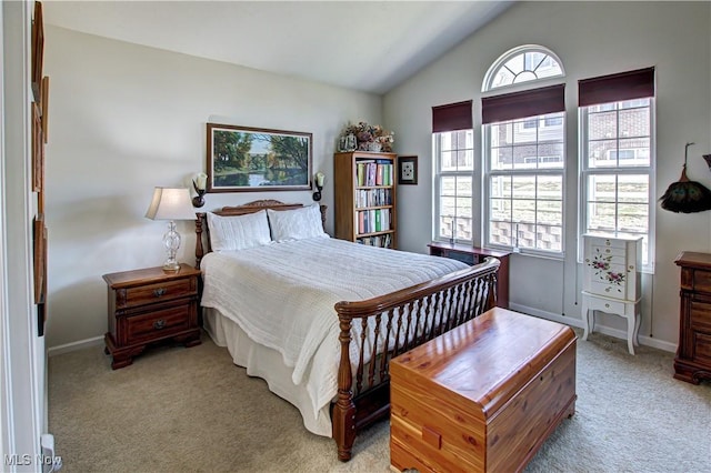 bedroom featuring light colored carpet, vaulted ceiling, and baseboards