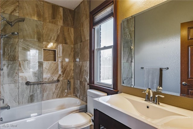 bathroom featuring a textured wall, vanity, toilet, and shower / bathtub combination