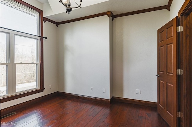 empty room featuring dark wood-style floors, ornamental molding, visible vents, and baseboards