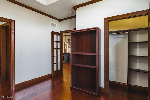 unfurnished bedroom with ornamental molding, visible vents, baseboards, and hardwood / wood-style flooring