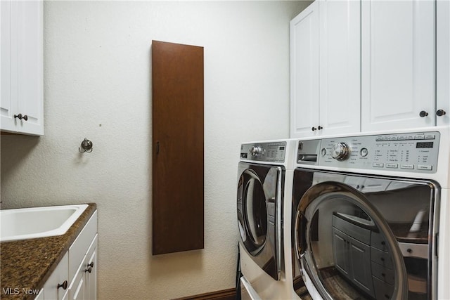 laundry room with a sink, a textured wall, washing machine and dryer, and cabinet space