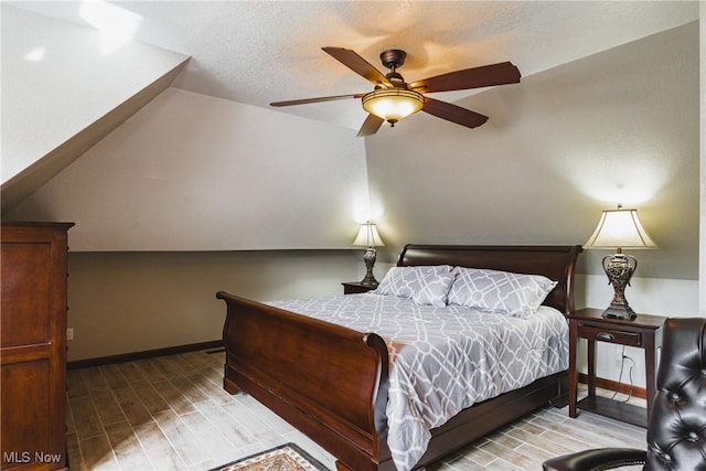 bedroom featuring a ceiling fan, wood tiled floor, vaulted ceiling, a textured ceiling, and baseboards