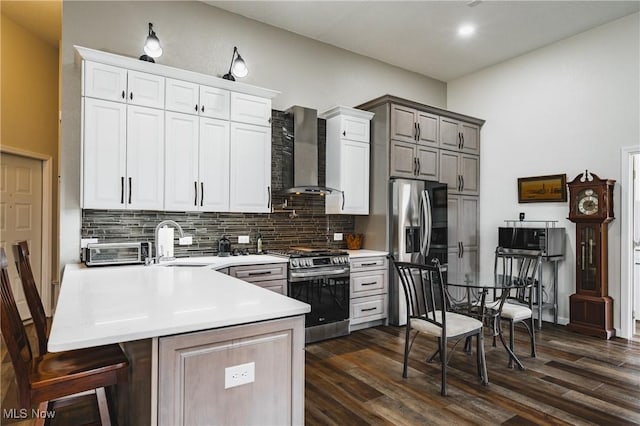 kitchen with tasteful backsplash, stainless steel appliances, light countertops, wall chimney range hood, and a sink