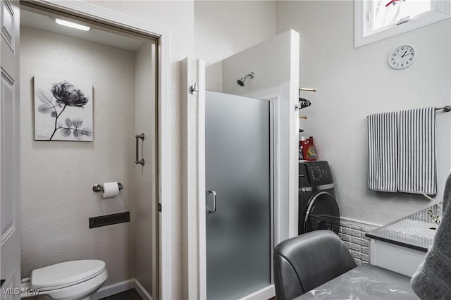 full bathroom with toilet, a stall shower, and washer / clothes dryer