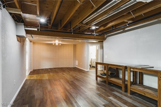 finished basement featuring baseboards, brick wall, and wood finished floors