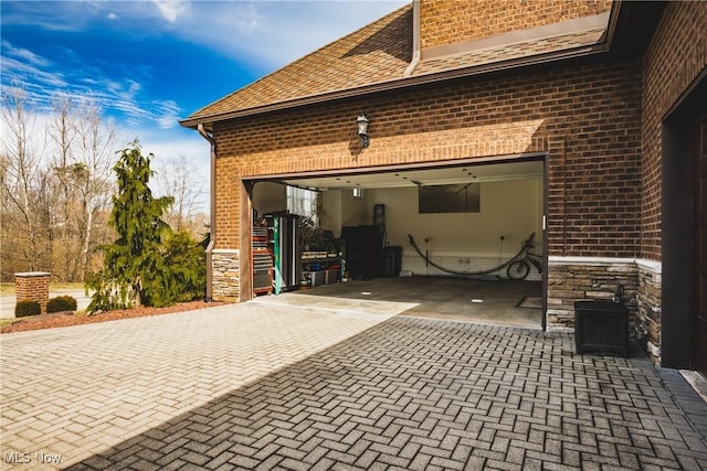 exterior space with a garage, stone siding, decorative driveway, and brick siding