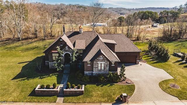 view of front of house with stone siding, decorative driveway, and a front yard