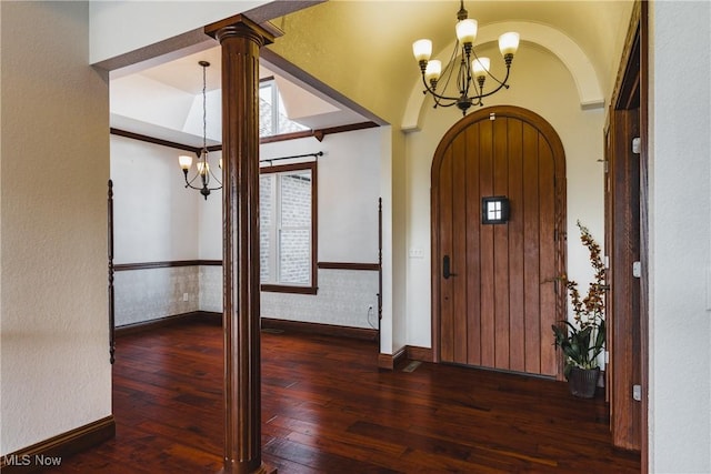 foyer featuring arched walkways, lofted ceiling, wood-type flooring, a chandelier, and baseboards