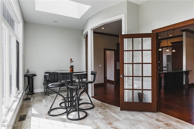 dining room with a skylight, baseboards, visible vents, wood finished floors, and french doors