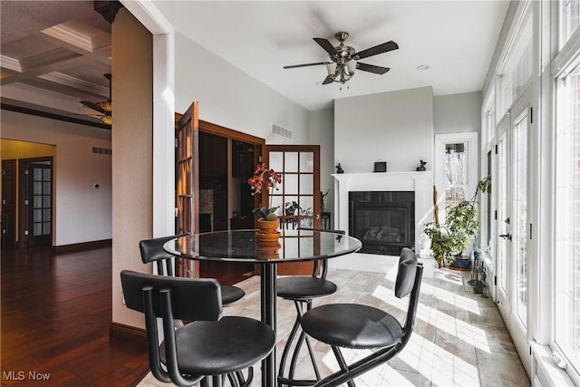 dining area with ceiling fan, a tiled fireplace, visible vents, and wood finished floors