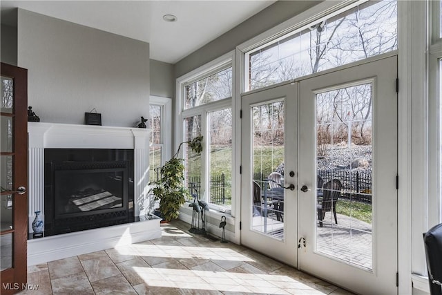 doorway to outside with a fireplace with raised hearth and french doors