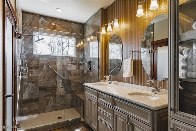 full bath featuring tiled shower, a sink, and double vanity