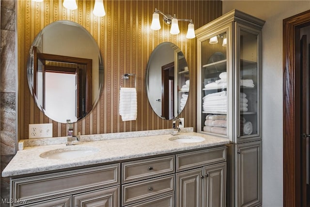 bathroom with double vanity, a sink, and wallpapered walls