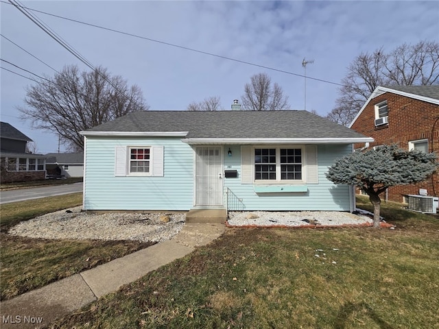 bungalow with central air condition unit, a front lawn, and roof with shingles