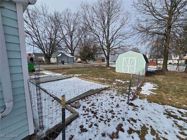 yard covered in snow featuring an outdoor structure, a storage shed, and fence