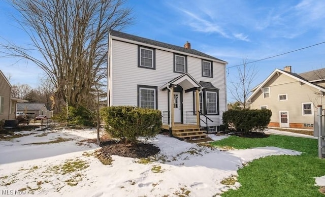 colonial-style house featuring a front yard and a chimney