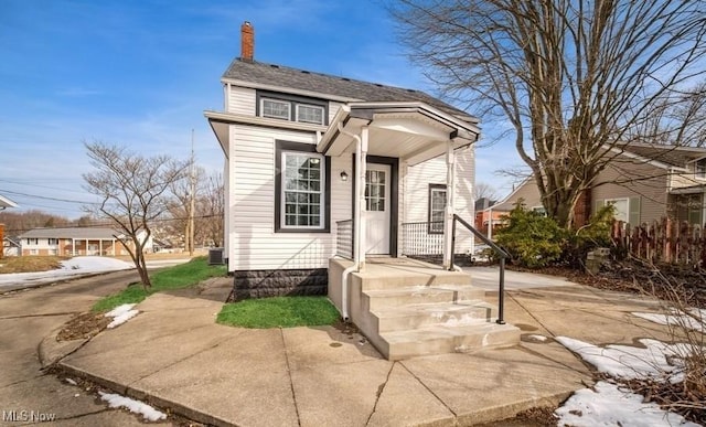 view of front of house featuring cooling unit and a chimney