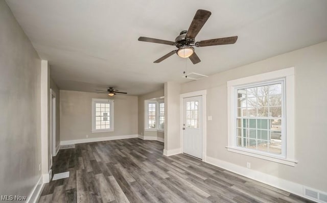 unfurnished living room with dark wood-style floors, visible vents, baseboards, and a ceiling fan