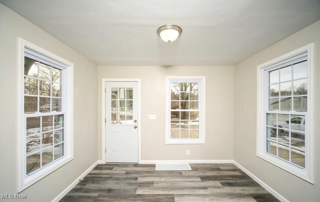 doorway with dark wood-type flooring and baseboards