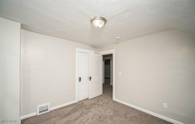 interior space with lofted ceiling, carpet, visible vents, and baseboards