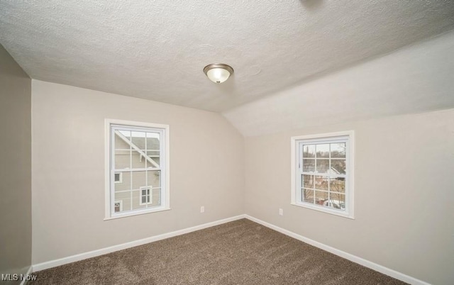 unfurnished room featuring baseboards, vaulted ceiling, and dark colored carpet