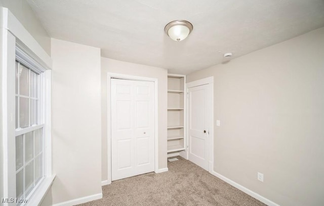 unfurnished bedroom featuring a closet, carpet, and baseboards