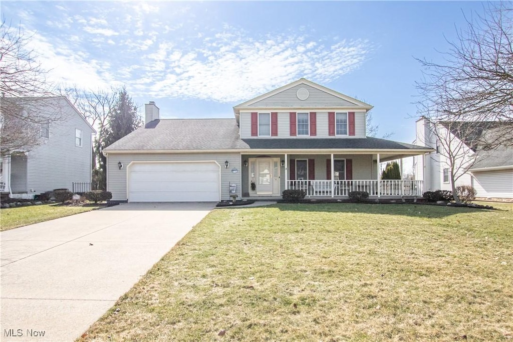 view of front of property with a porch, an attached garage, driveway, a front lawn, and a chimney