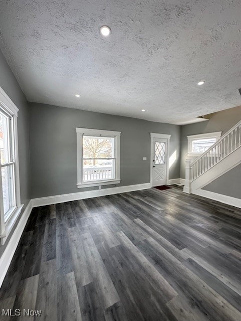 foyer with dark wood-style floors, plenty of natural light, stairs, and baseboards