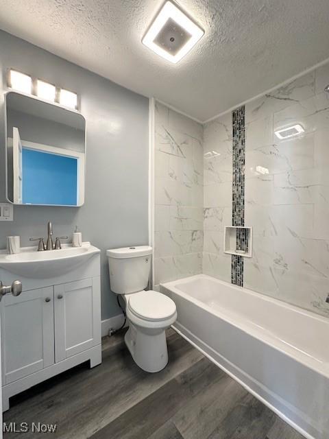 full bathroom with bathtub / shower combination, toilet, vanity, a textured ceiling, and wood finished floors