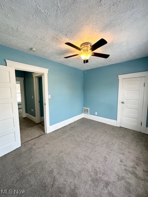 carpeted empty room featuring visible vents, ceiling fan, a textured ceiling, and baseboards