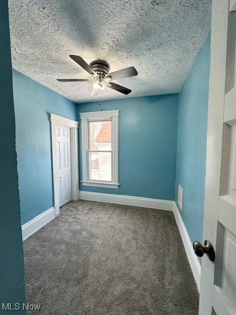 unfurnished bedroom featuring baseboards, ceiling fan, a textured ceiling, carpet floors, and a closet