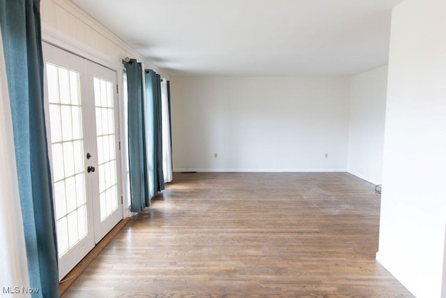 unfurnished room featuring baseboards, wood finished floors, and french doors