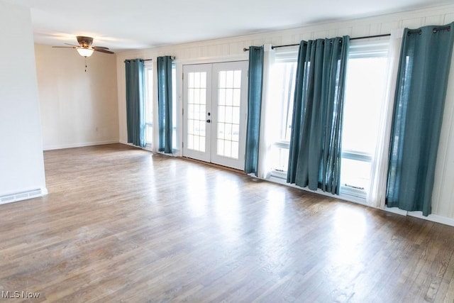 empty room with baseboards, a ceiling fan, wood finished floors, and french doors