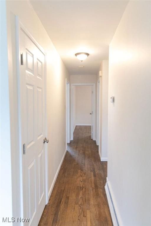 hallway featuring baseboards and dark wood finished floors