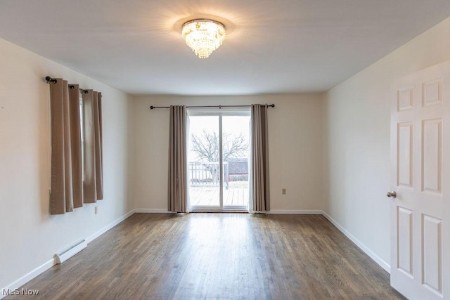 empty room featuring a baseboard radiator, baseboards, and wood finished floors