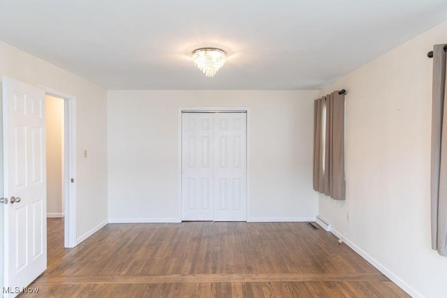 unfurnished bedroom with a closet, baseboards, and wood finished floors