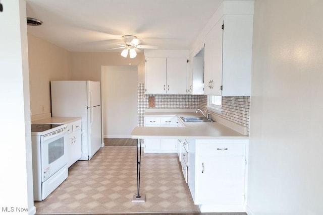 kitchen with white appliances, white cabinets, decorative backsplash, light countertops, and a sink