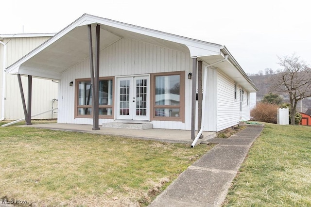 rear view of property featuring a lawn and french doors