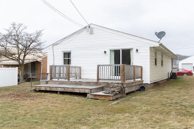 rear view of house featuring fence, central AC unit, a deck, and a yard