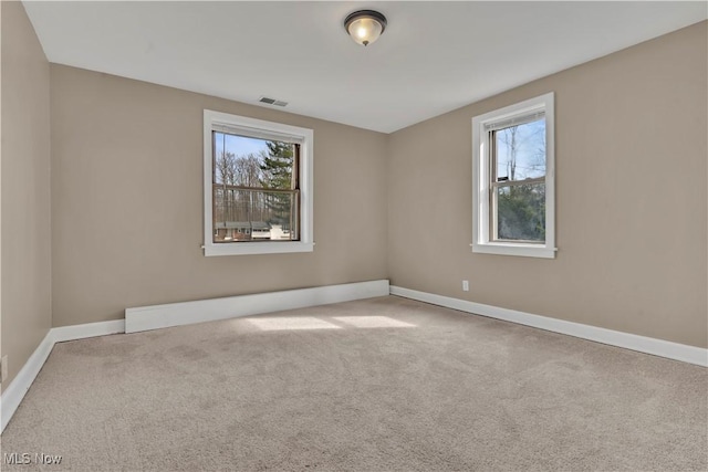 carpeted empty room with a wealth of natural light, visible vents, and baseboards