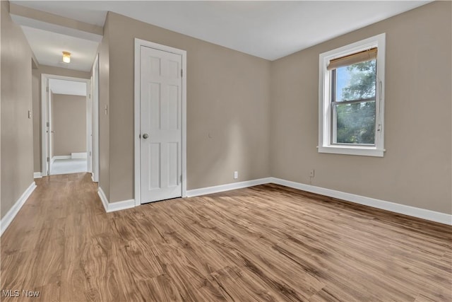 unfurnished bedroom with a closet, wood finished floors, and baseboards