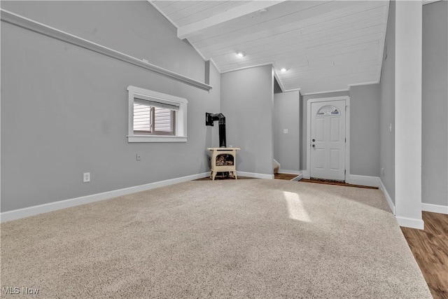 foyer featuring vaulted ceiling with beams, a wood stove, and baseboards