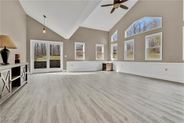 unfurnished living room featuring ceiling fan, high vaulted ceiling, a wainscoted wall, and wood finished floors