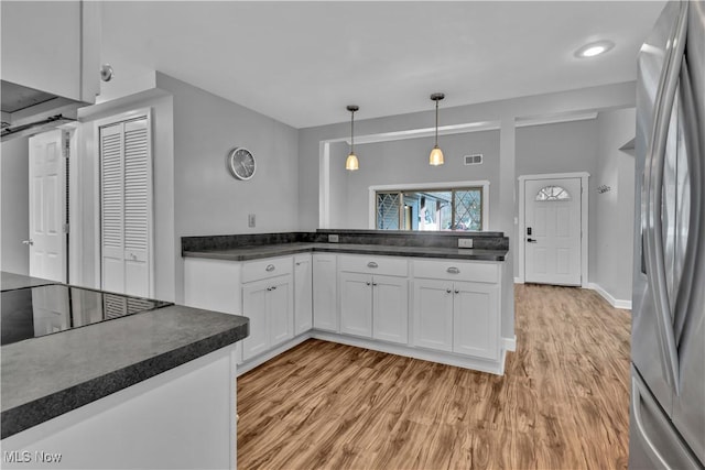 kitchen featuring visible vents, light wood-style floors, white cabinets, freestanding refrigerator, and dark countertops